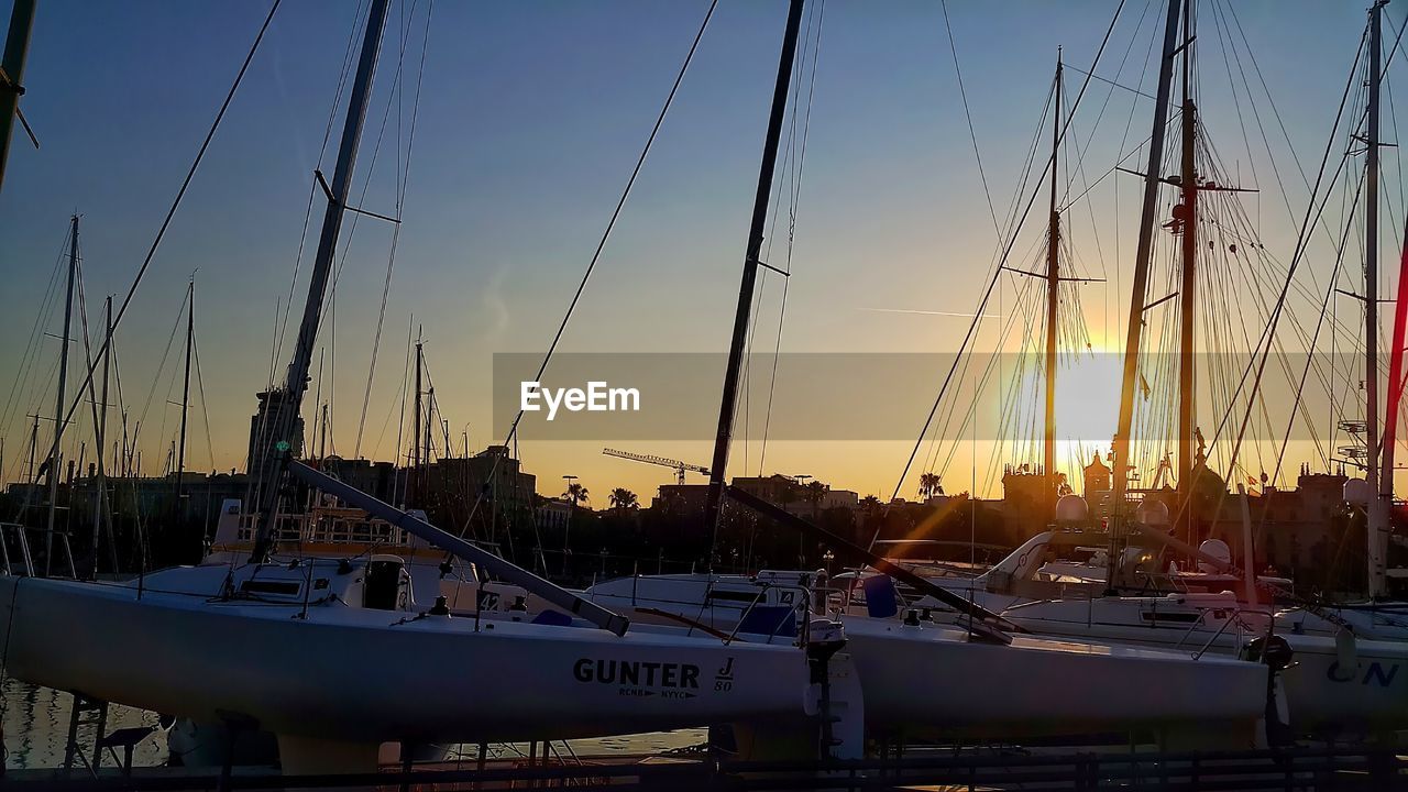 Side view of moored boats against sunset