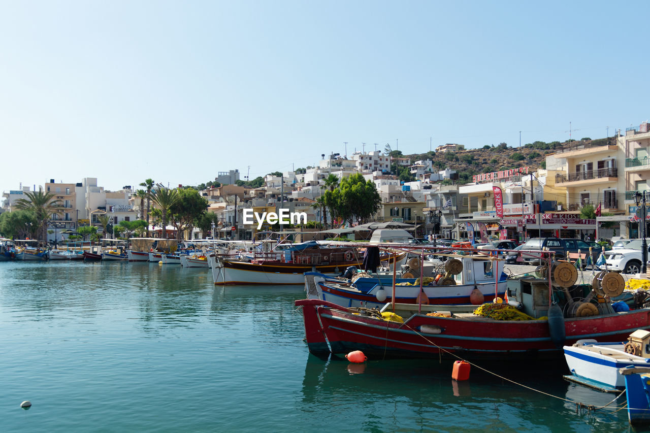 Sailboats moored in harbor against buildings in city