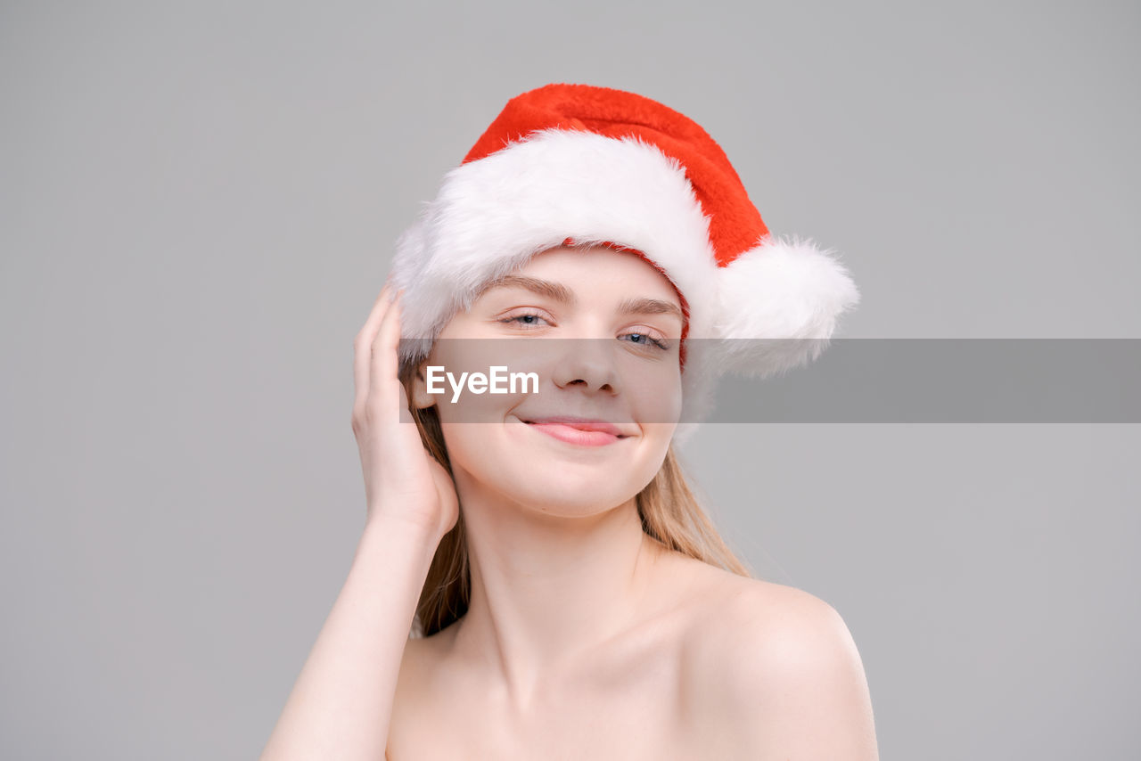 Christmas santa hat isolated female portrait. smiling happy girl on gray