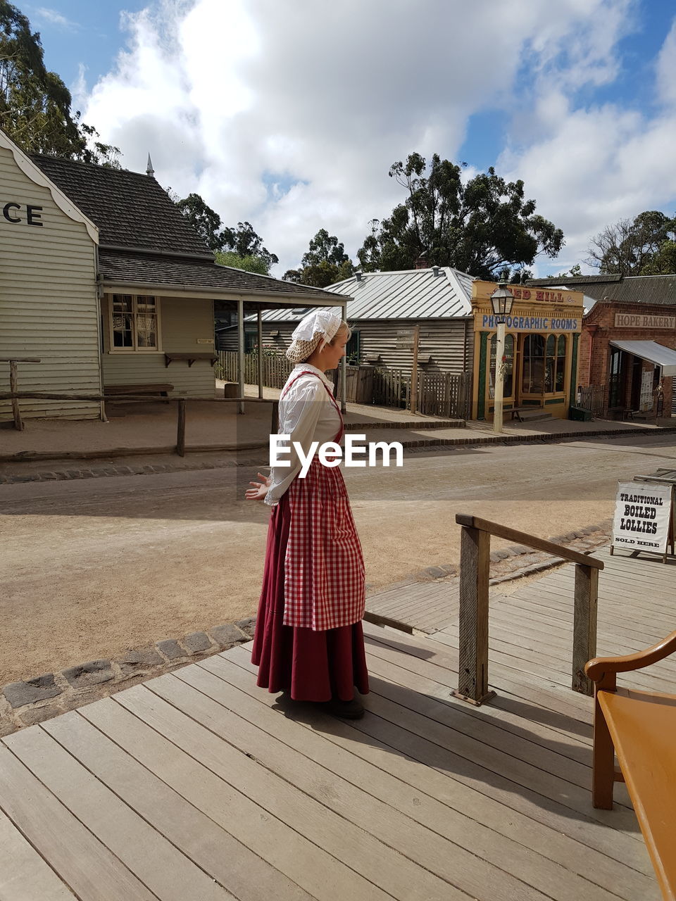 REAR VIEW OF WOMAN STANDING AGAINST BUILDINGS