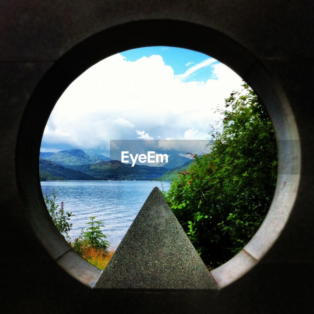 Scenic view of sea and mountains seen from circular window