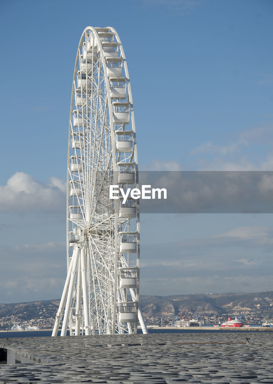 Ferris wheel by sea against sky