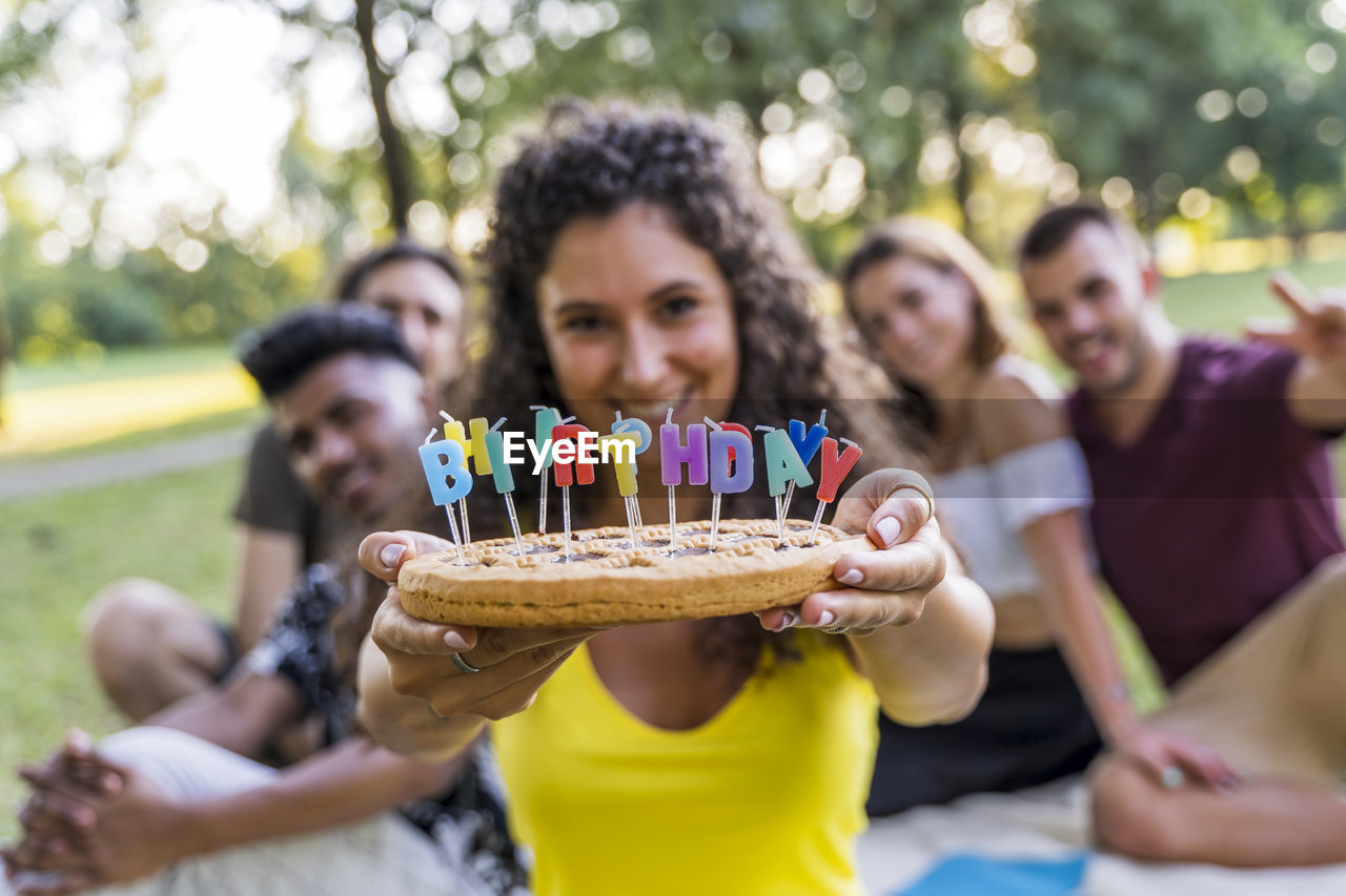 Portrait of cheerful woman with friends sitting outdoors