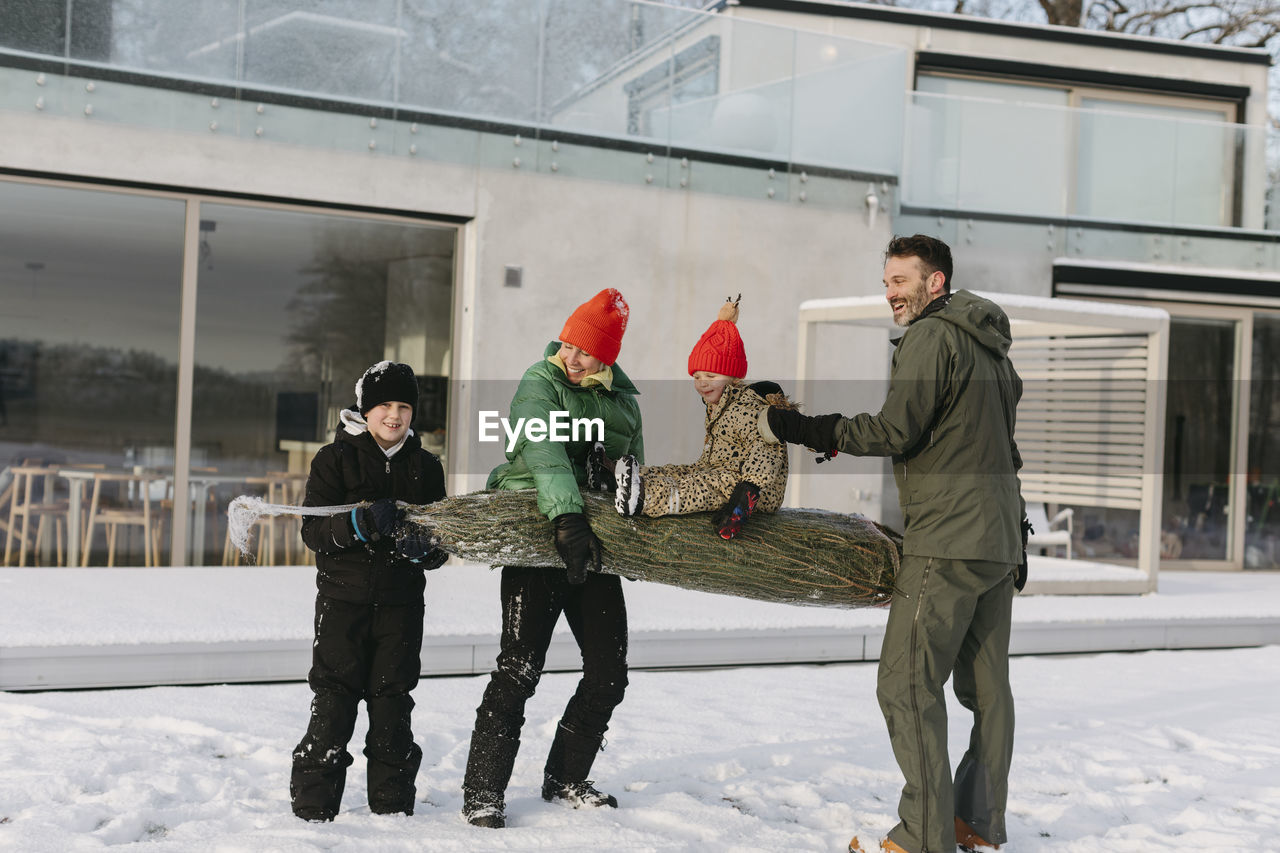 Family carrying christmas tree at winter