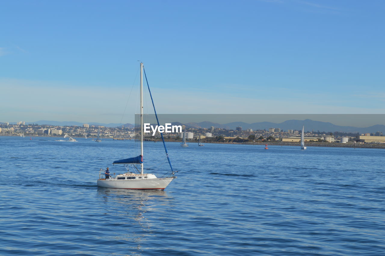 Sailboats sailing in sea against clear blue sky