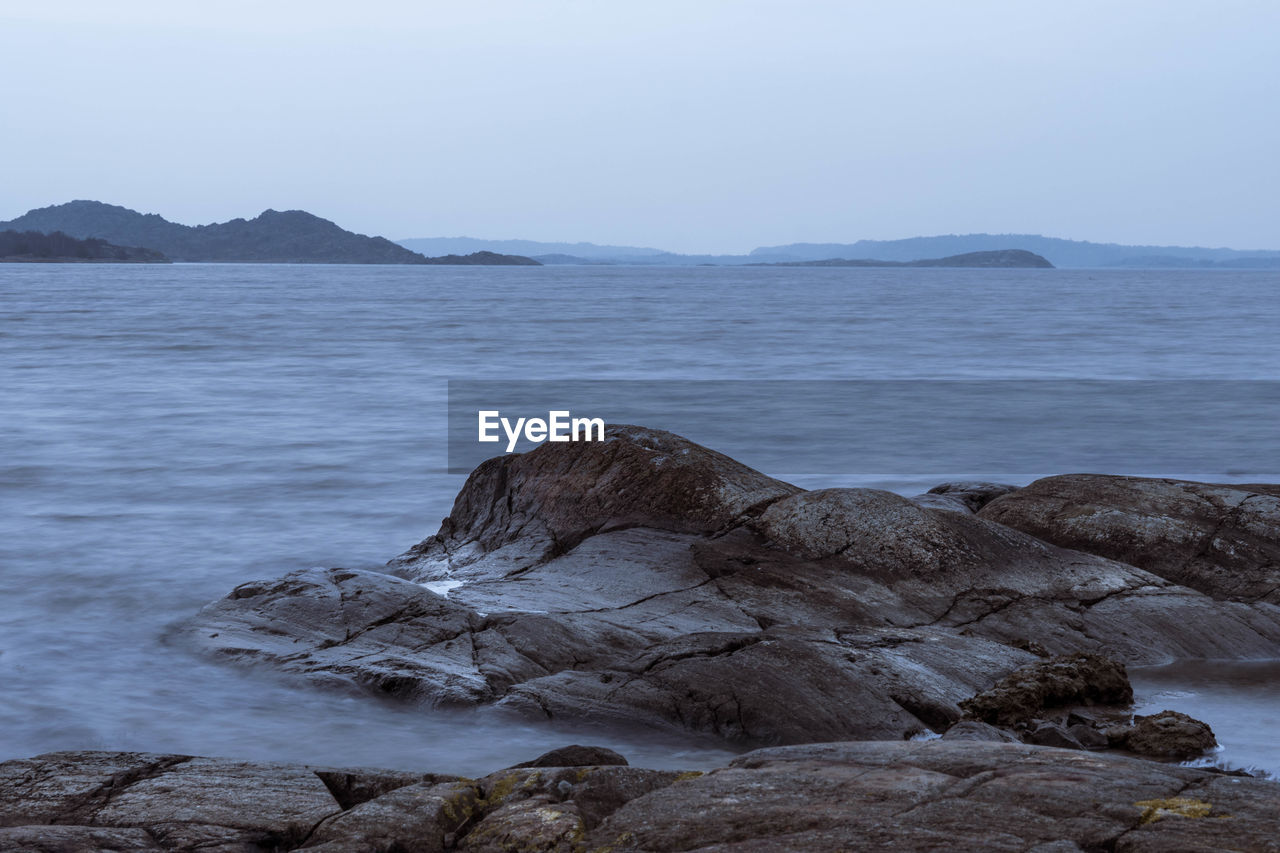 ROCK FORMATIONS ON SHORE AGAINST SKY