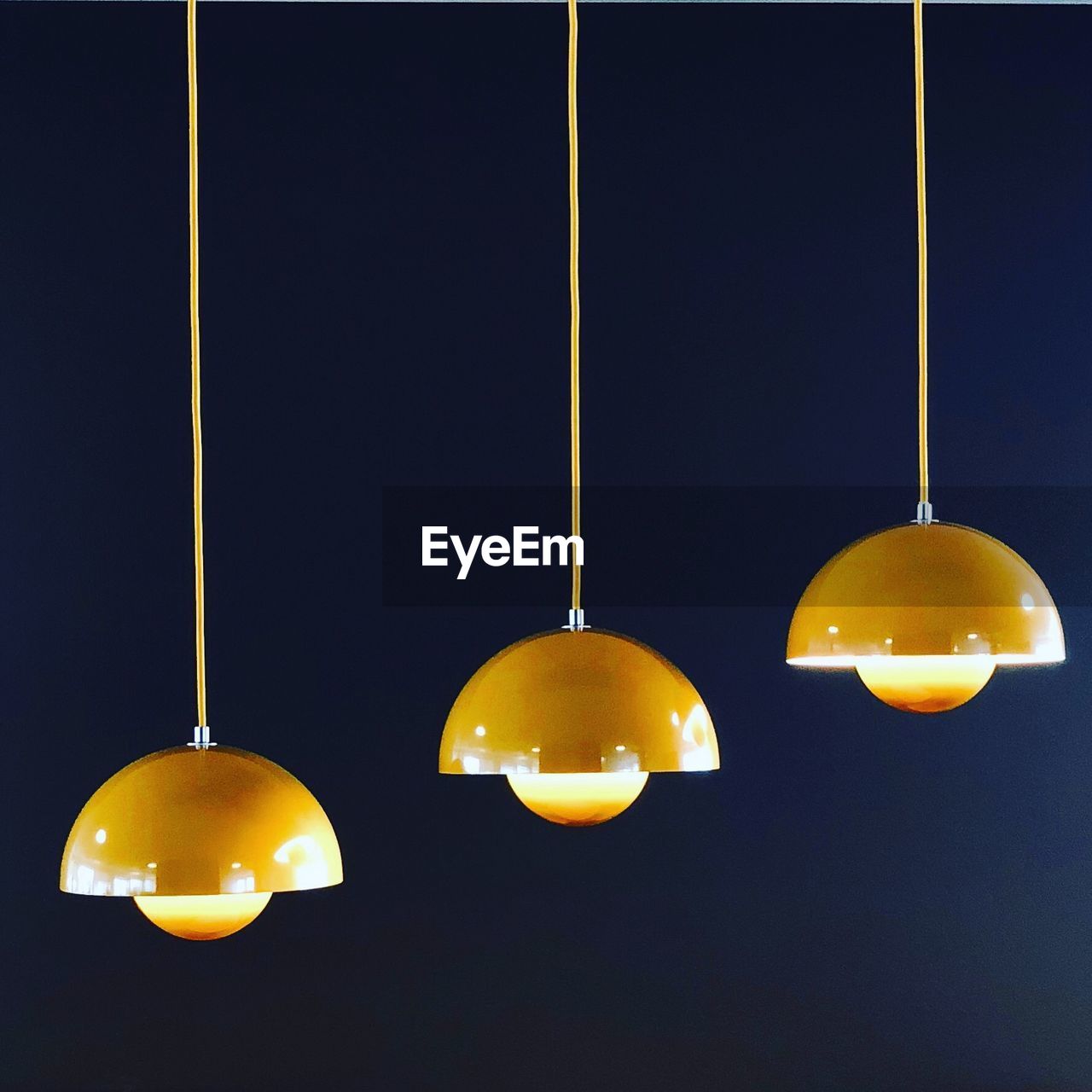 Low angle view of illuminated pendant lights hanging against black background