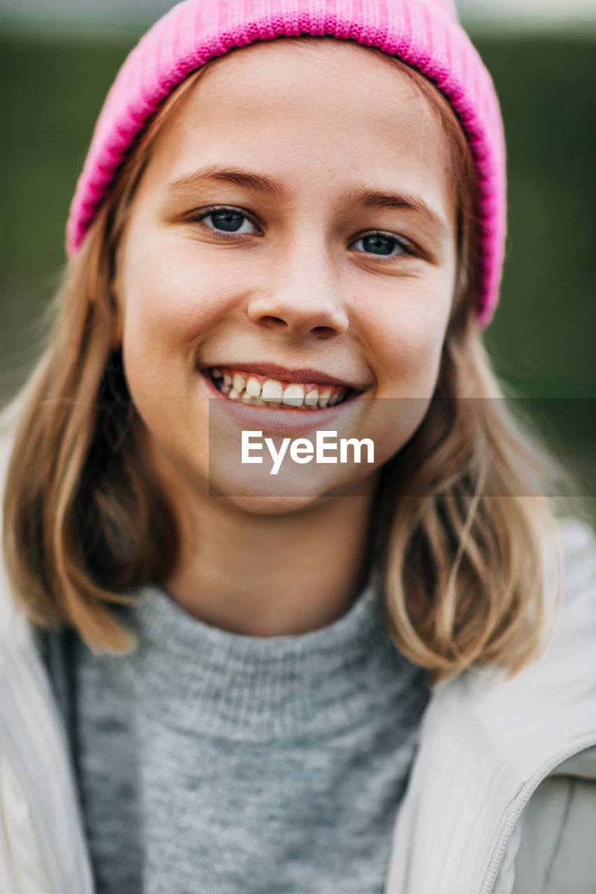 Portrait of smiling stylish teenage girl wearing pink fashion cap