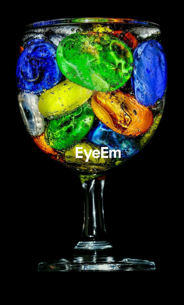 Close-up of multi colored drink in glass over black background