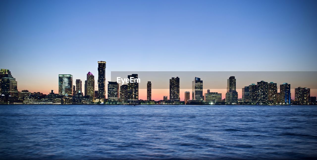 City at waterfront against blue sky