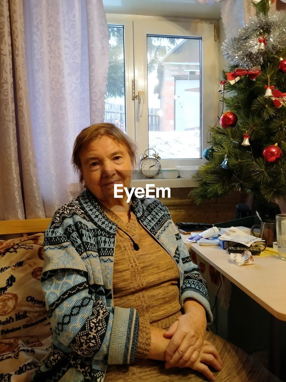 PORTRAIT OF HAPPY WOMAN SITTING AT HOME