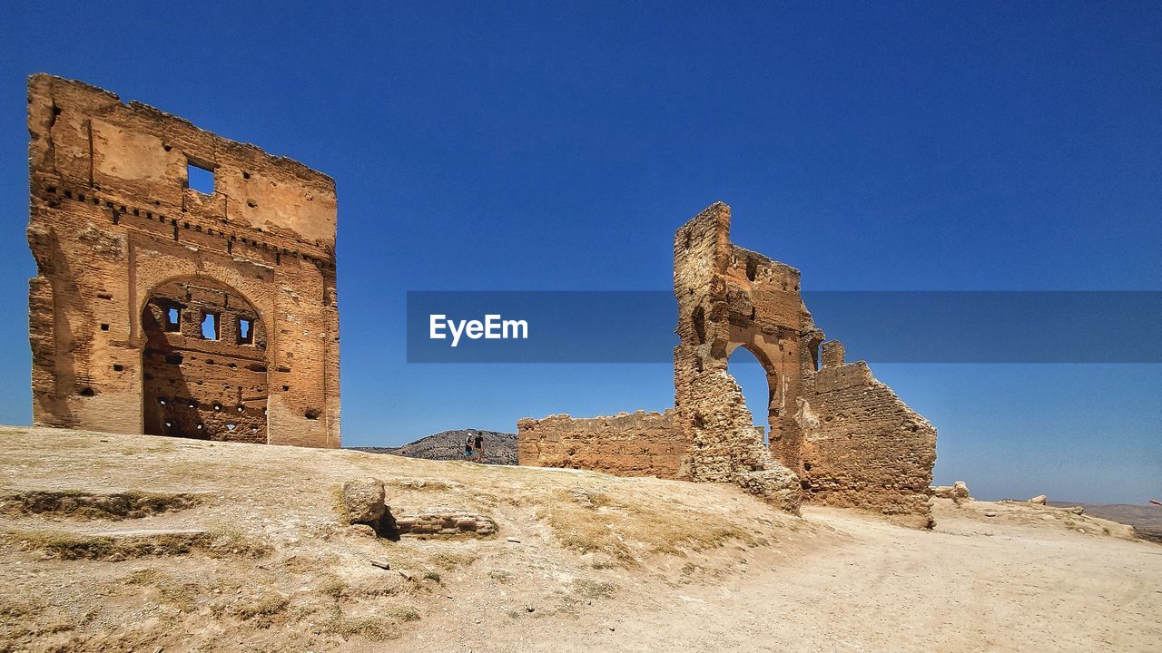 Low angle view of old ruins against clear blue sky