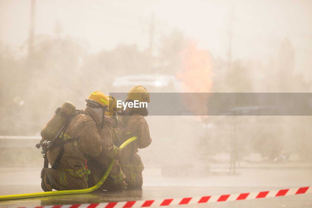 Firefighters spraying water on burning car in city