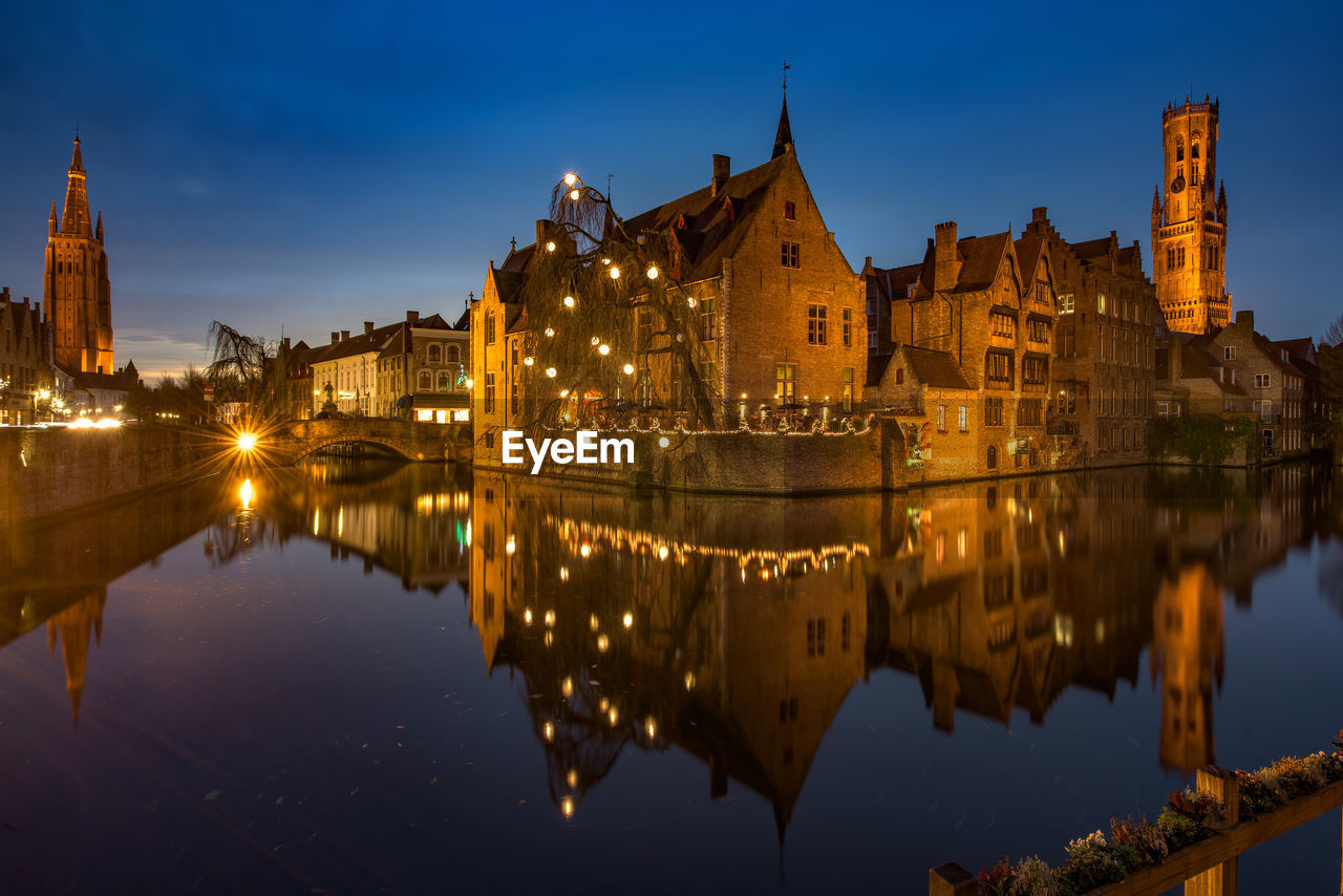 Illuminated church reflecting in canal at dusk