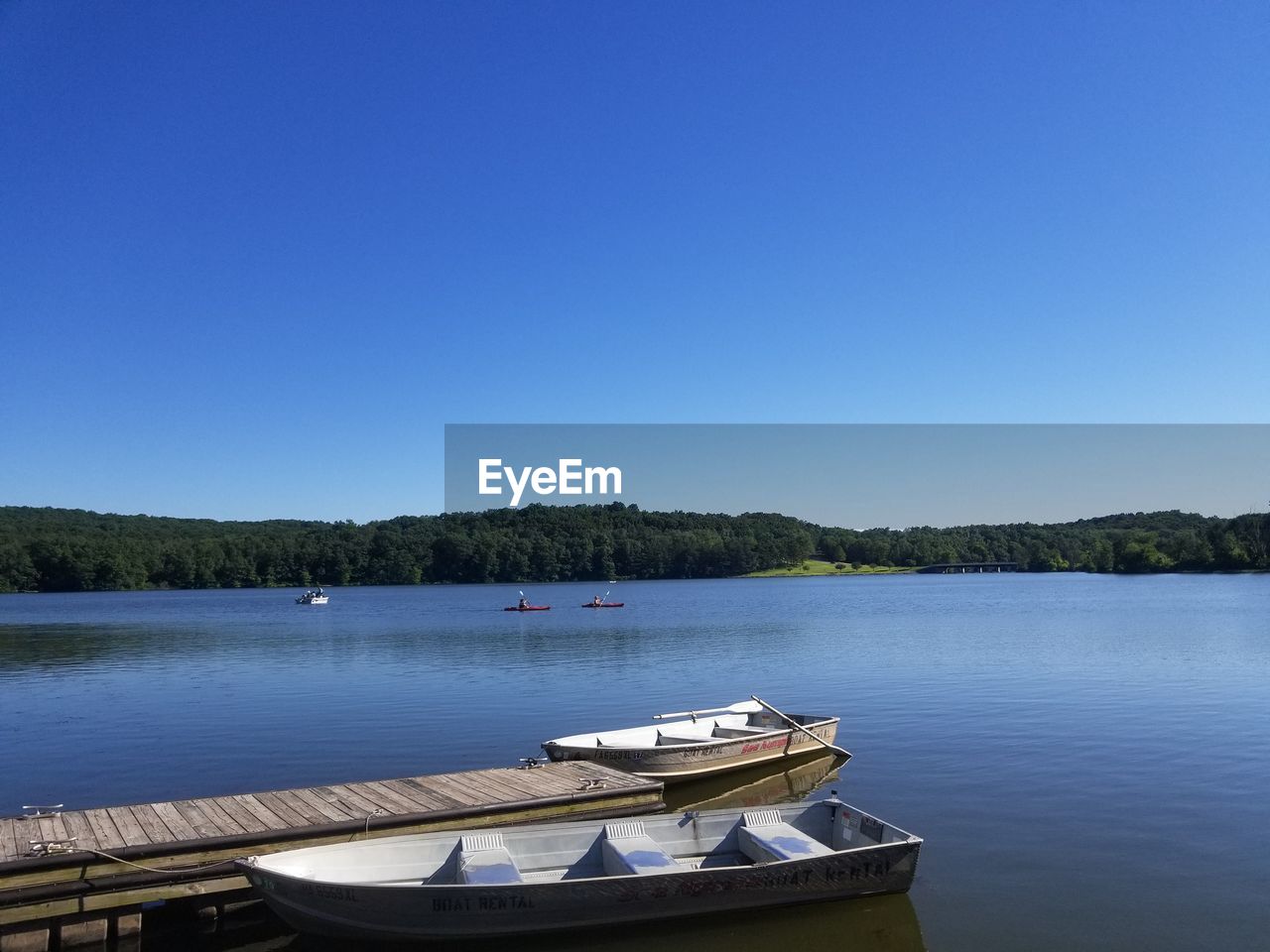 Boats moored in lake against clear blue sky