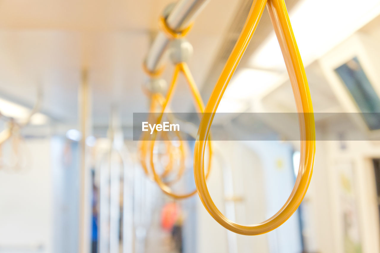 Close-up of yellow handles hanging in metro train