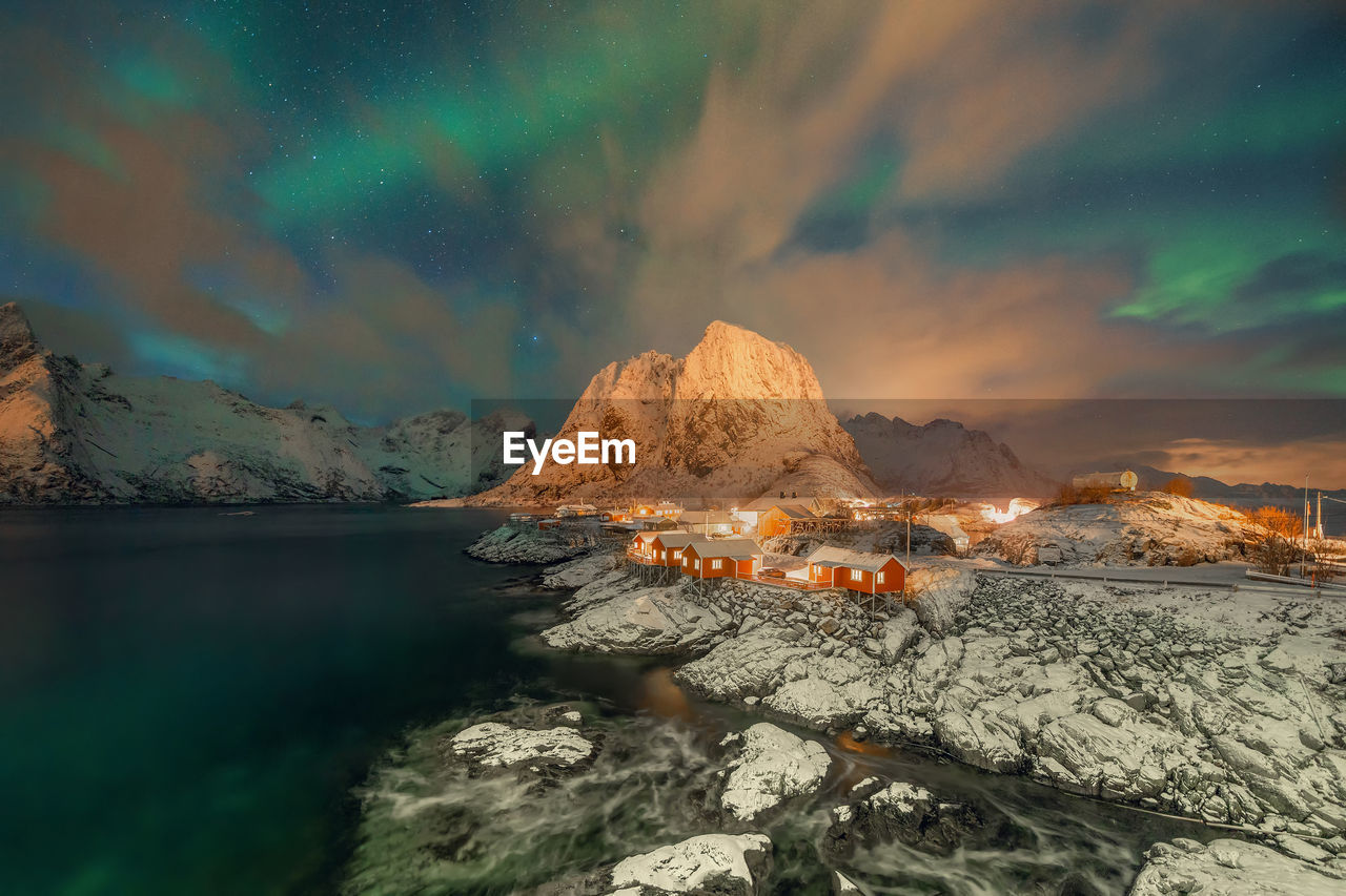 Scenic view of sea and mountains against sky at night