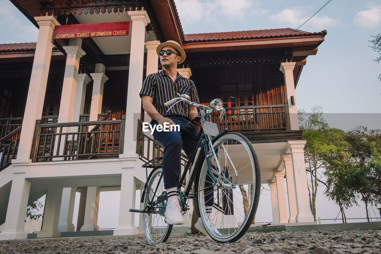 FULL LENGTH OF MAN STANDING BY BICYCLE