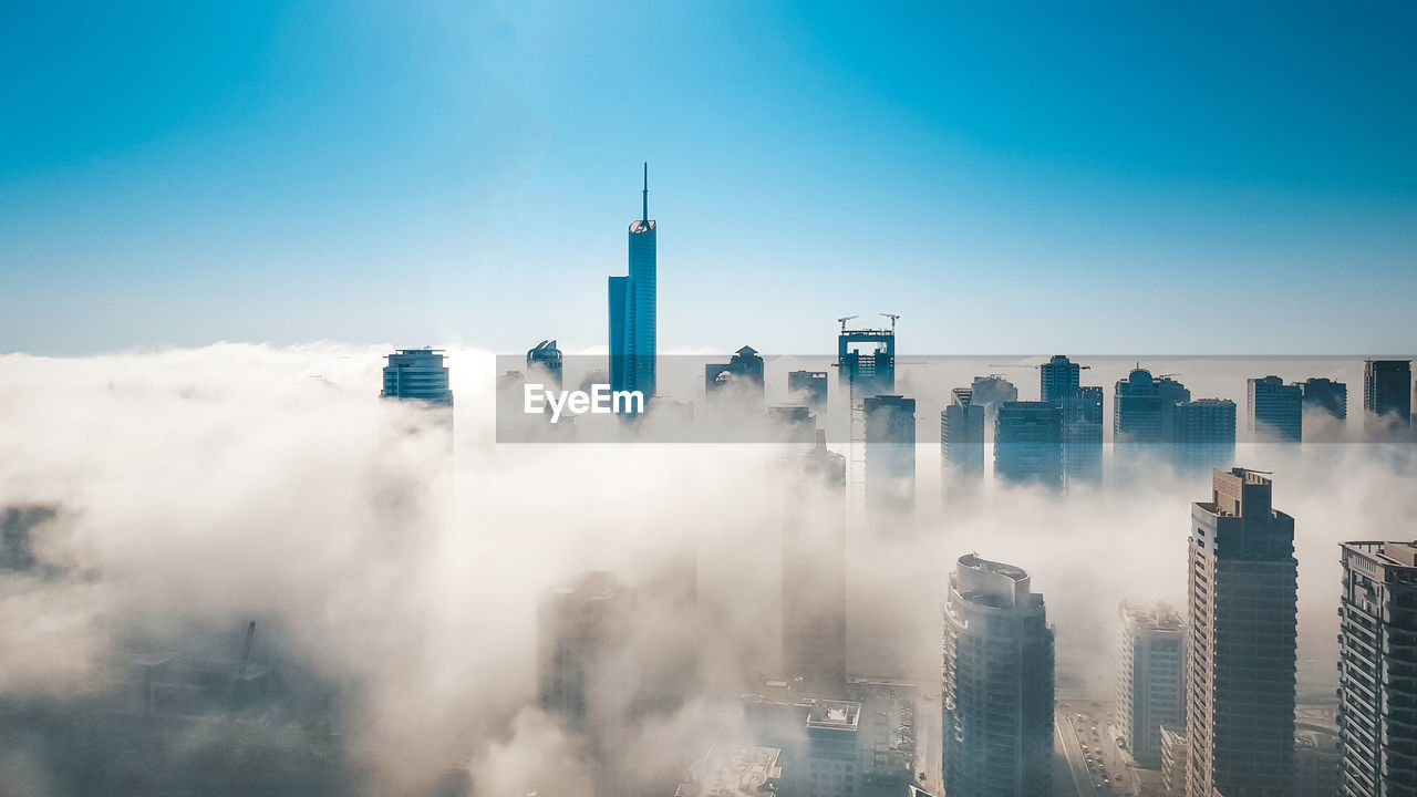 Panoramic view of dubai marina buildings in fog against cloudy sky