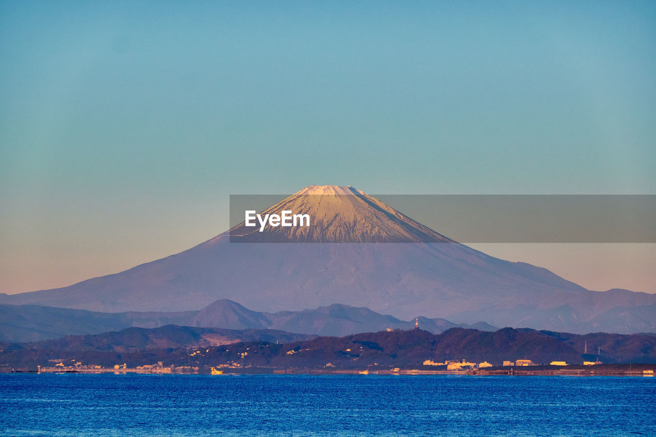 Scenic view of sea and snowcapped mountain against sky during sunrise