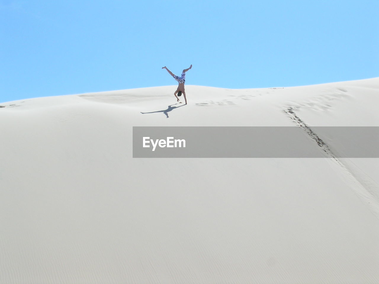 Low angle view of man practicing handstand on sand dune
