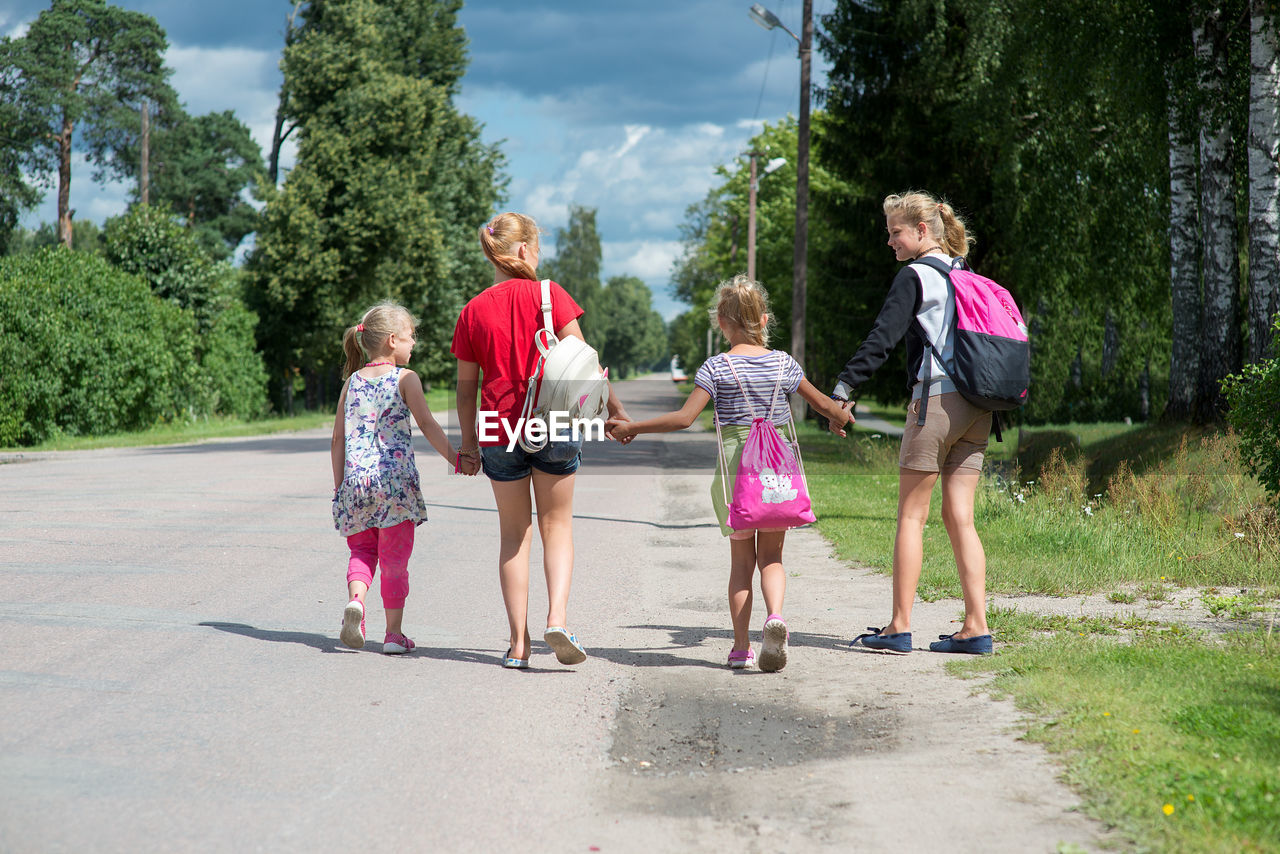 Rear view of children walking on road