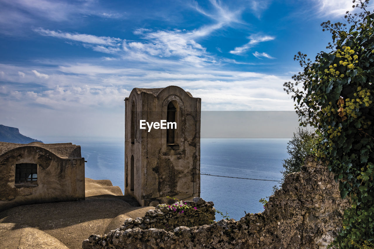 BUILT STRUCTURE BY SEA AGAINST BLUE SKY