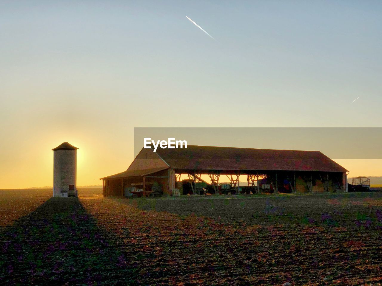 HOUSE ON FIELD AGAINST SKY AT SUNSET