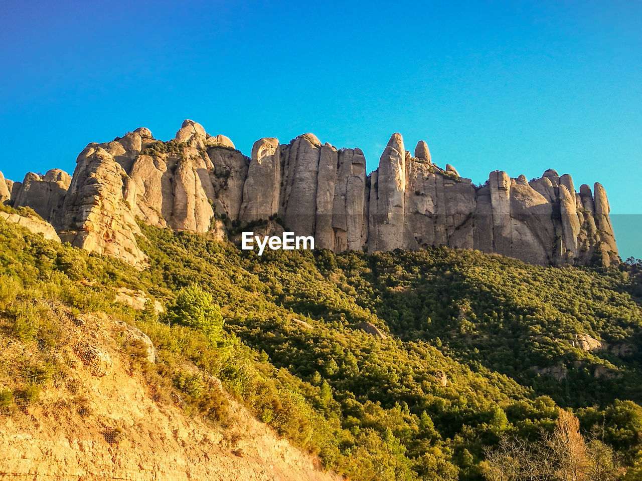 Panoramic view of rocks and trees against blue sky