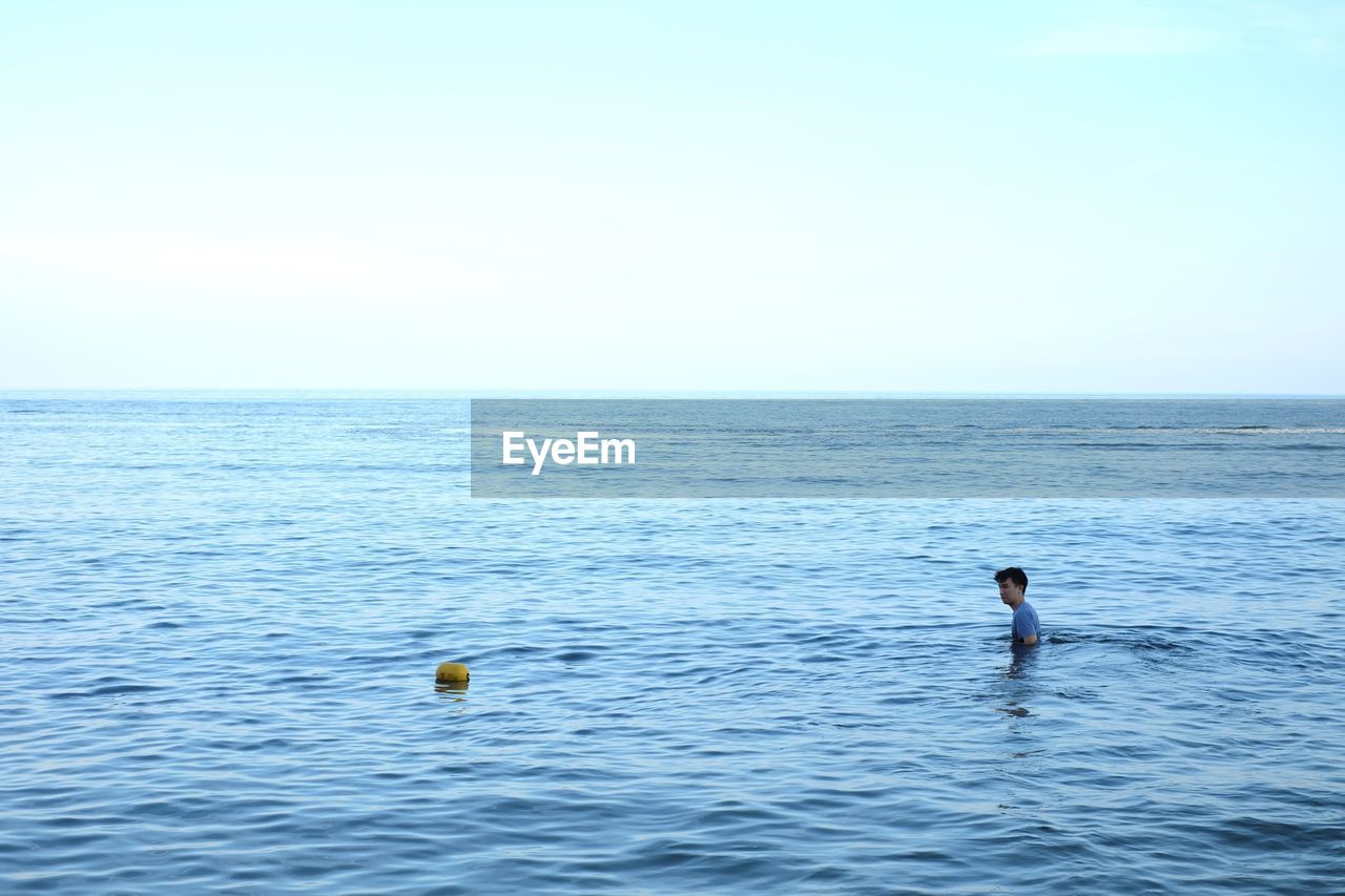 MAN SWIMMING IN SEA AGAINST SKY