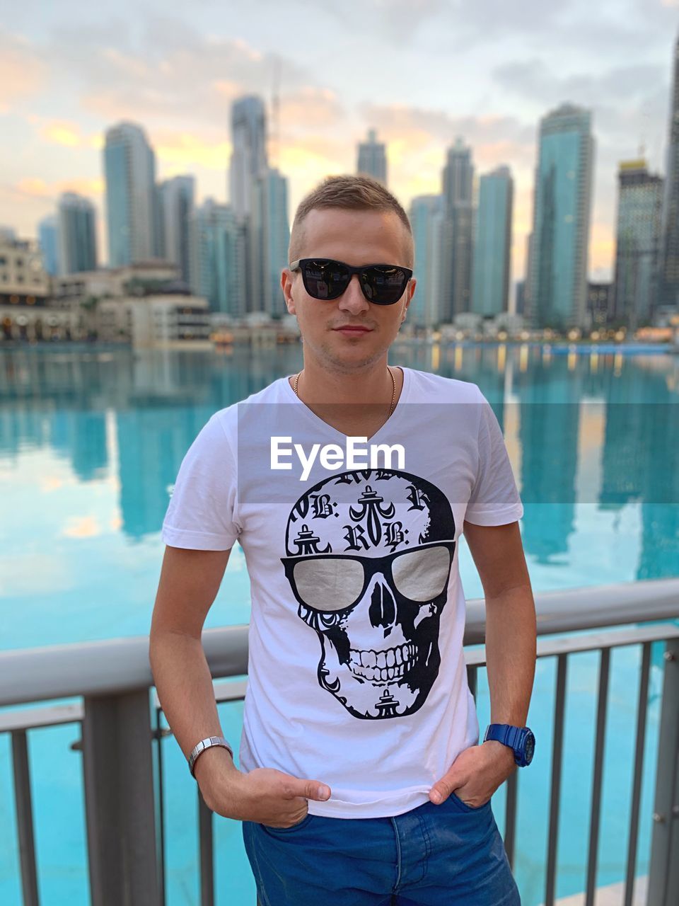 PORTRAIT OF MATURE MAN WEARING SUNGLASSES STANDING BY RAILING AGAINST SEA