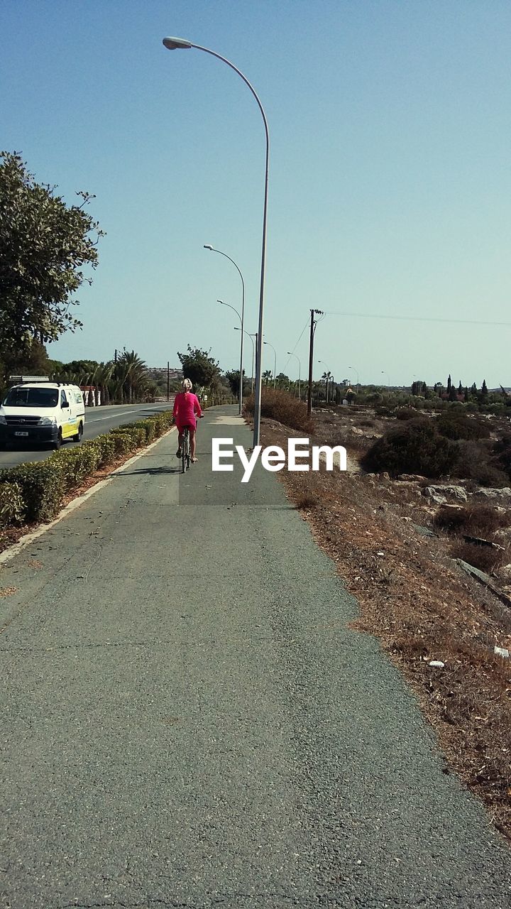 REAR VIEW OF MAN ON ROAD