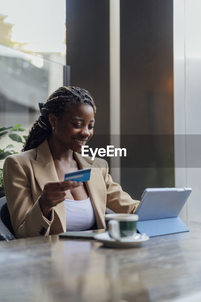 Businesswoman holding credit card and using tablet pc at cafe