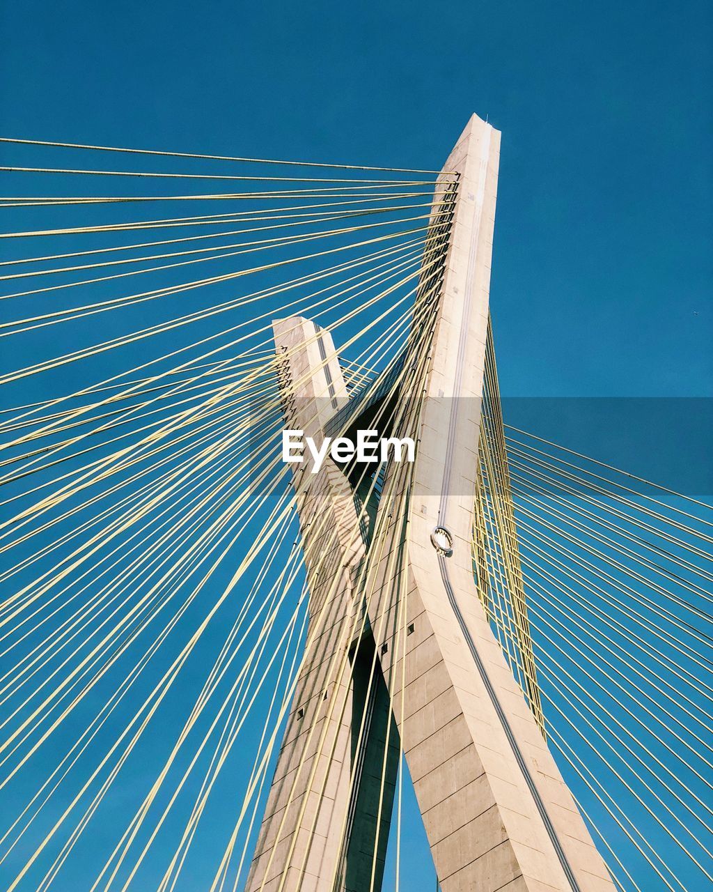 Low angle view of suspension bridge against blue sky