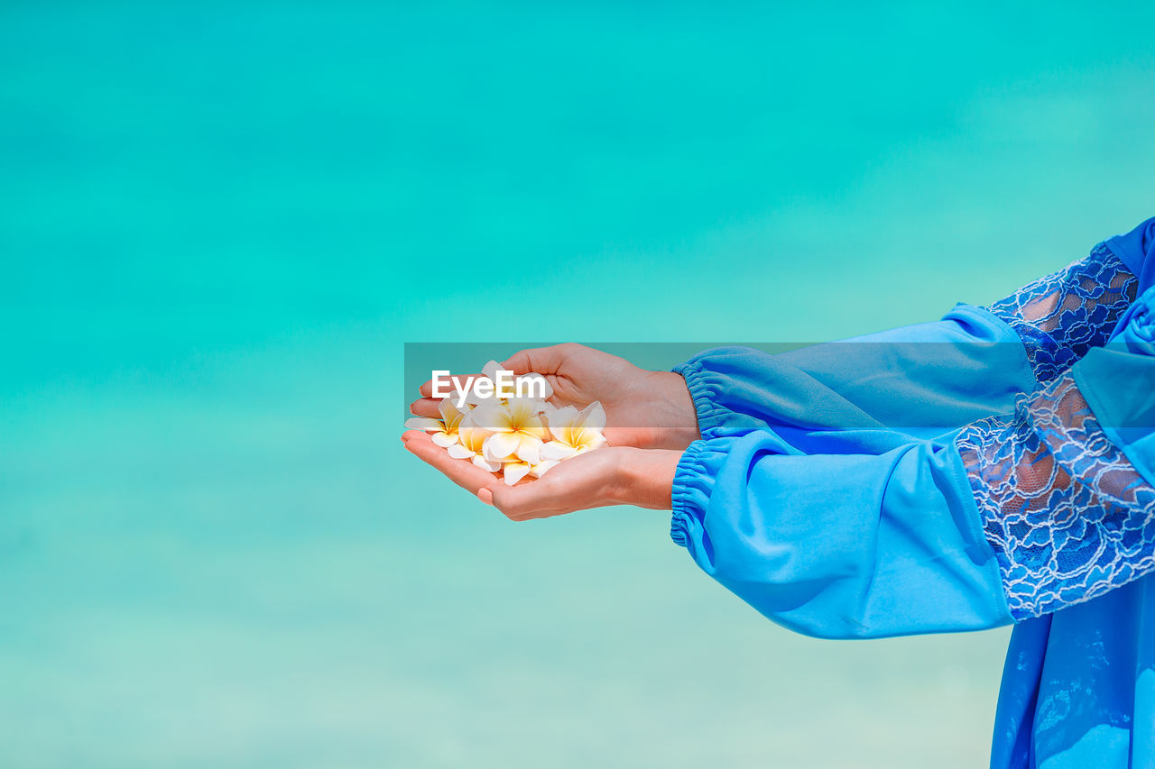 Midsection of woman holding ice cream against blue sky