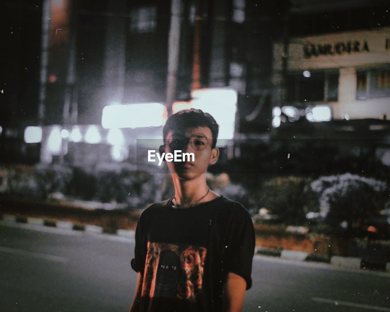 PORTRAIT OF YOUNG MAN STANDING ON CITY AT NIGHT