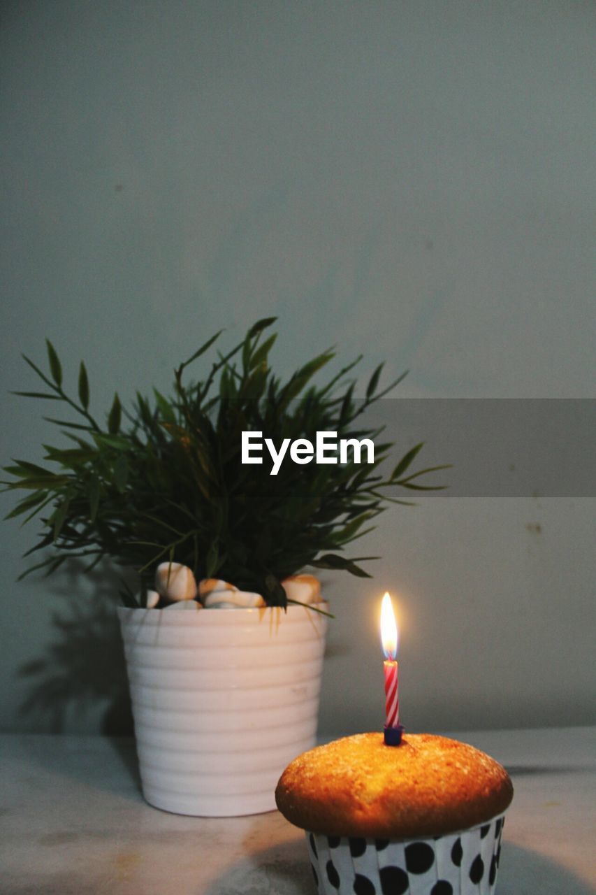 CLOSE-UP OF ILLUMINATED CANDLES ON TABLE