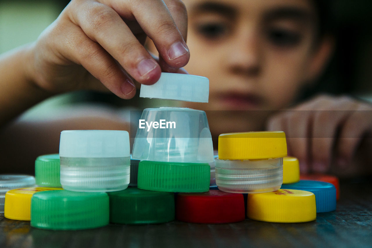 Boy playing with bottle caps on table