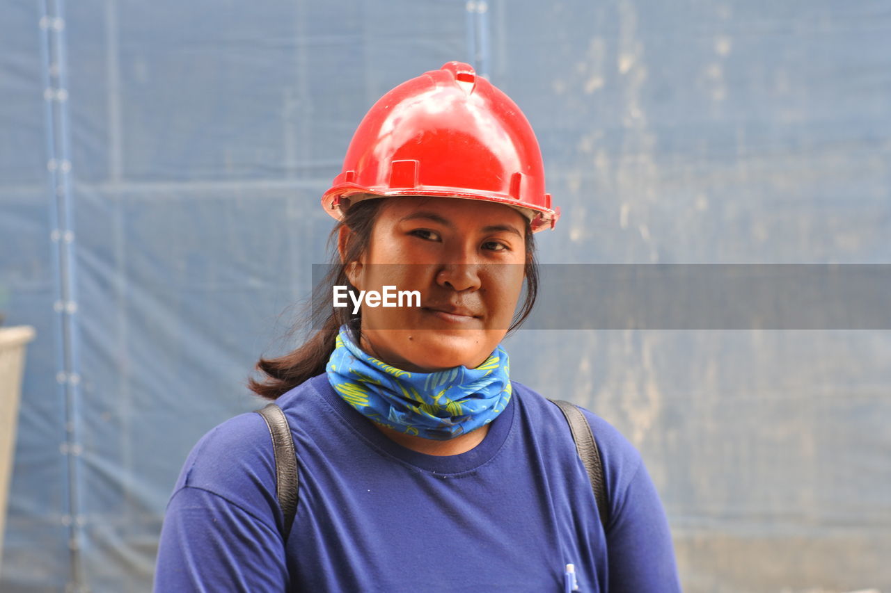 Portrait of smiling young woman wearing red hardhat