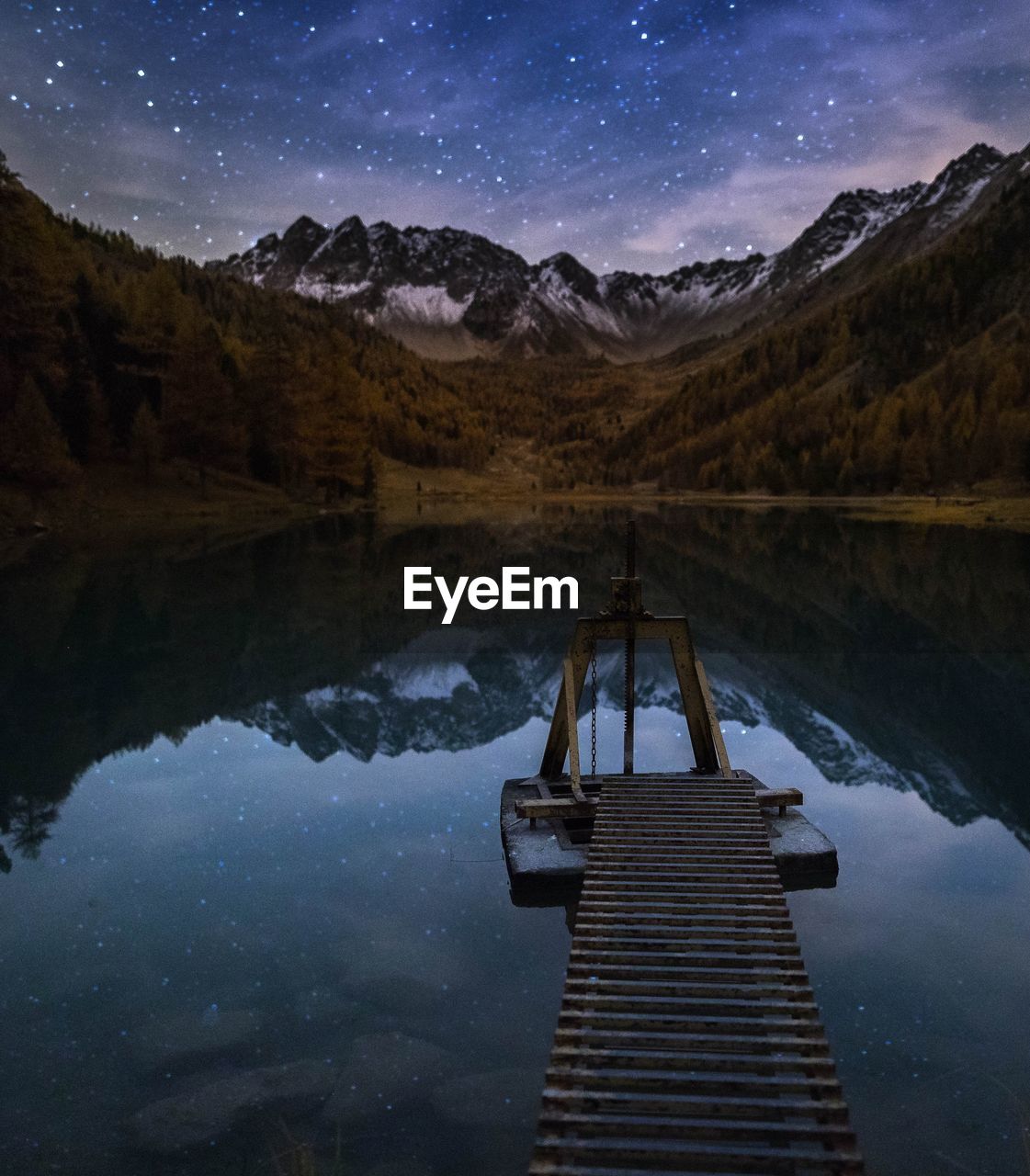 Scenic view of lake and mountains against sky at night