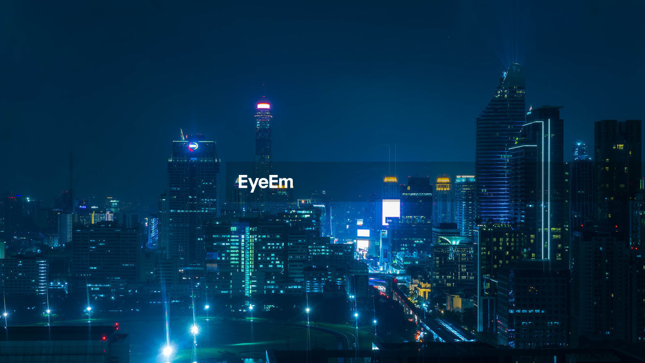 Illuminated buildings in city against sky at night