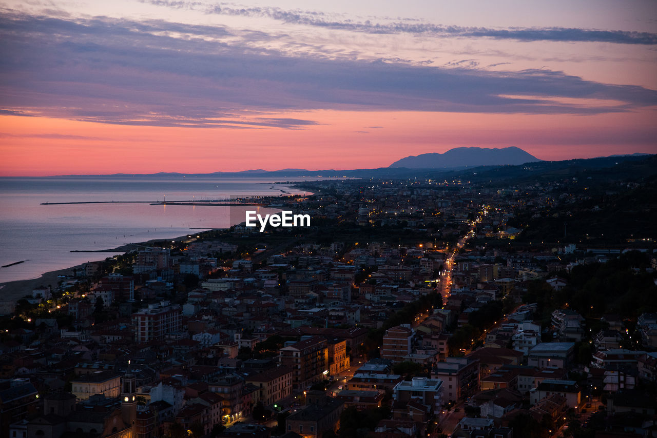 High angle view of townscape by sea against sky at sunrise.