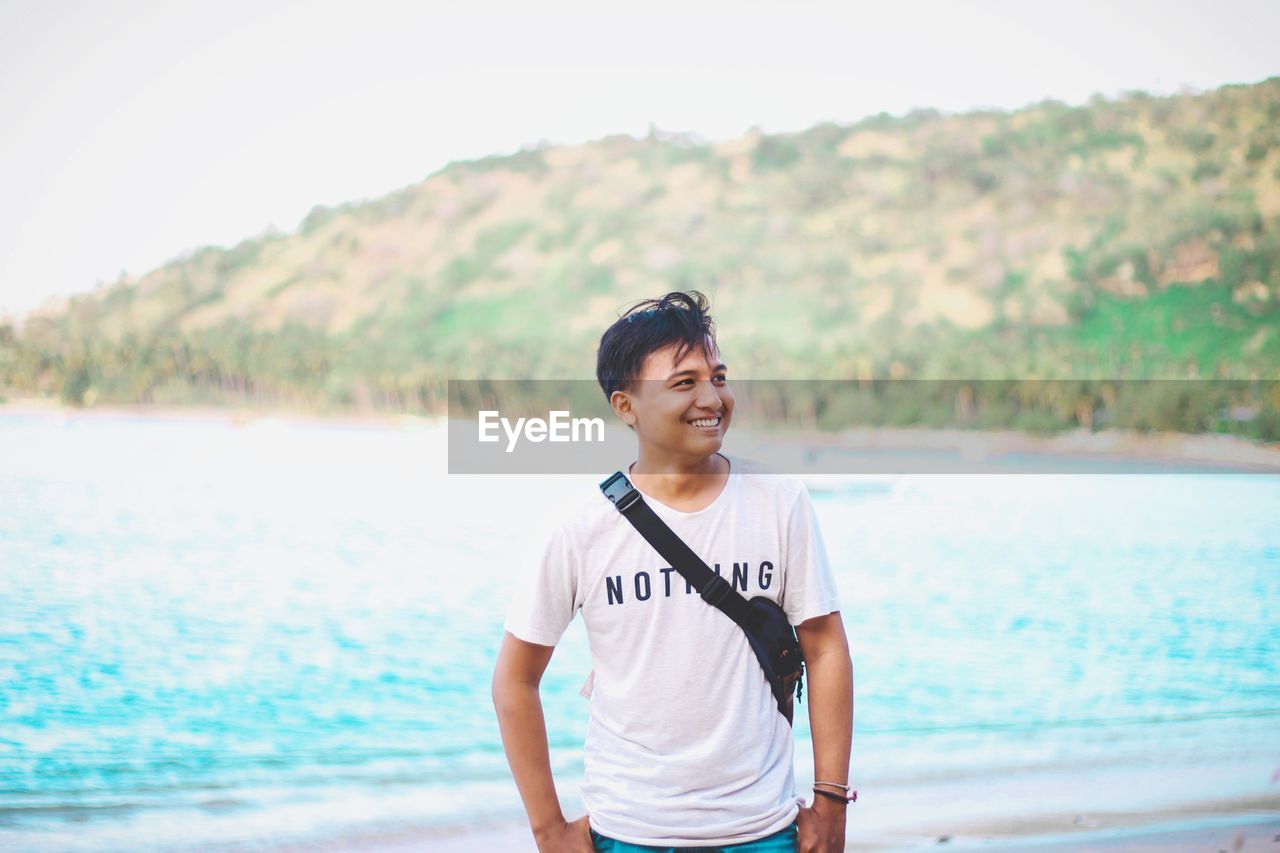 PORTRAIT OF SMILING YOUNG MAN STANDING IN SEA