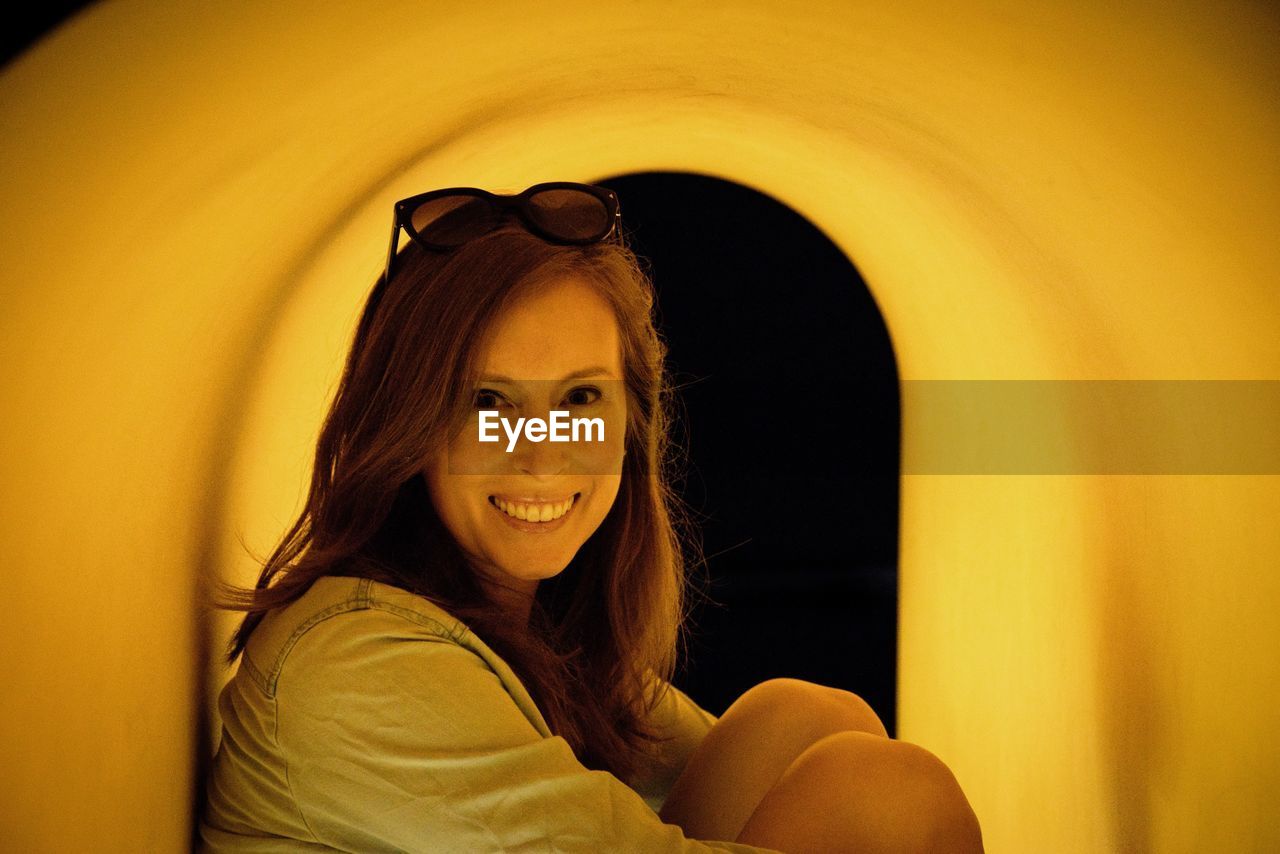 Portrait of smiling young woman sitting in tunnel