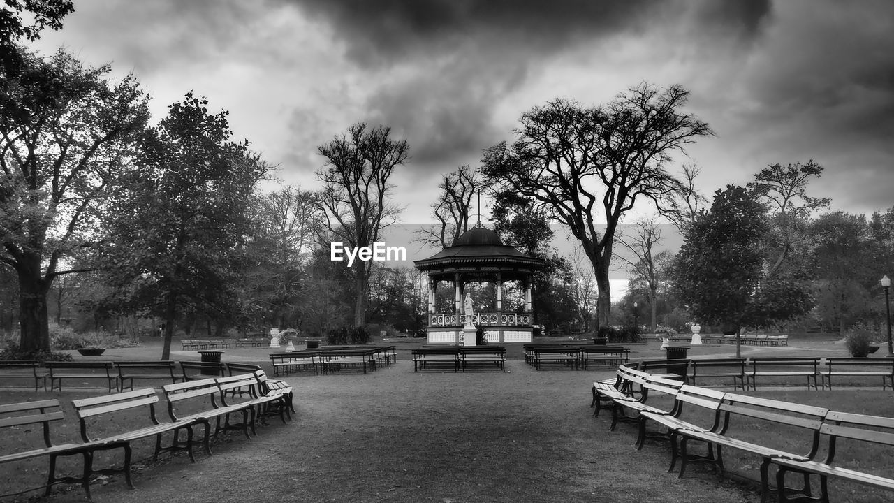 tree, plant, sky, architecture, cloud, nature, park, monochrome, black and white, bench, built structure, monochrome photography, park - man made space, travel destinations, water, urban area, seat, outdoors, cityscape, building exterior, no people, city, park bench, travel, day