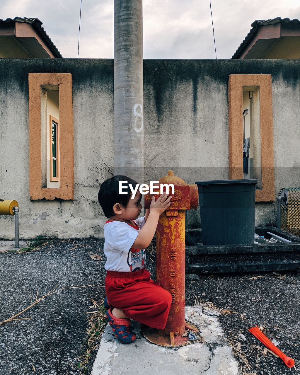 Full length of boy holding fire hydrant against building