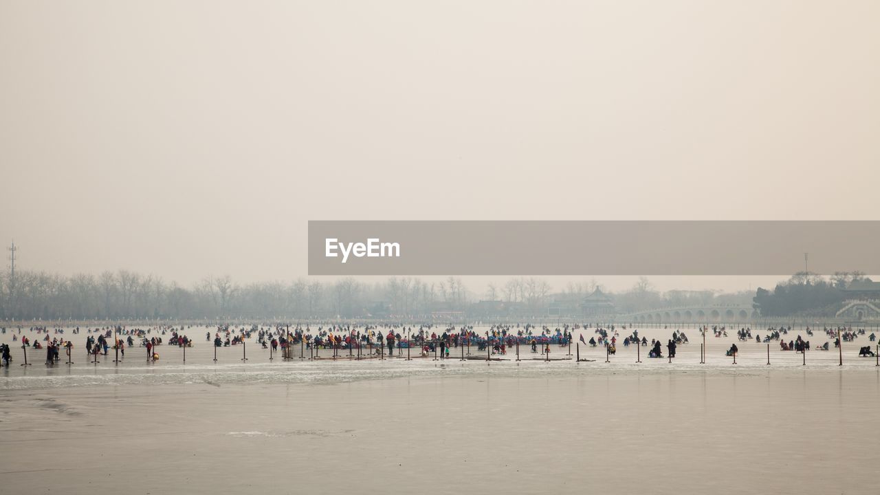 People at beach against clear sky