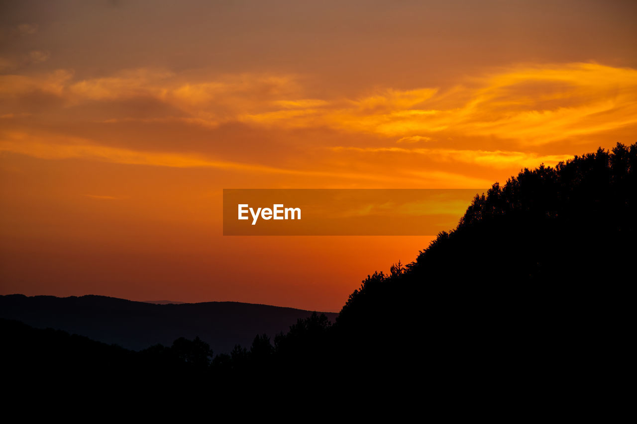 Scenic view of silhouette mountains against orange sky