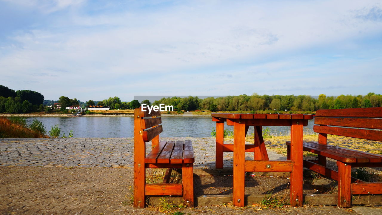 CHAIR AND TABLE BY LAKE AGAINST SKY