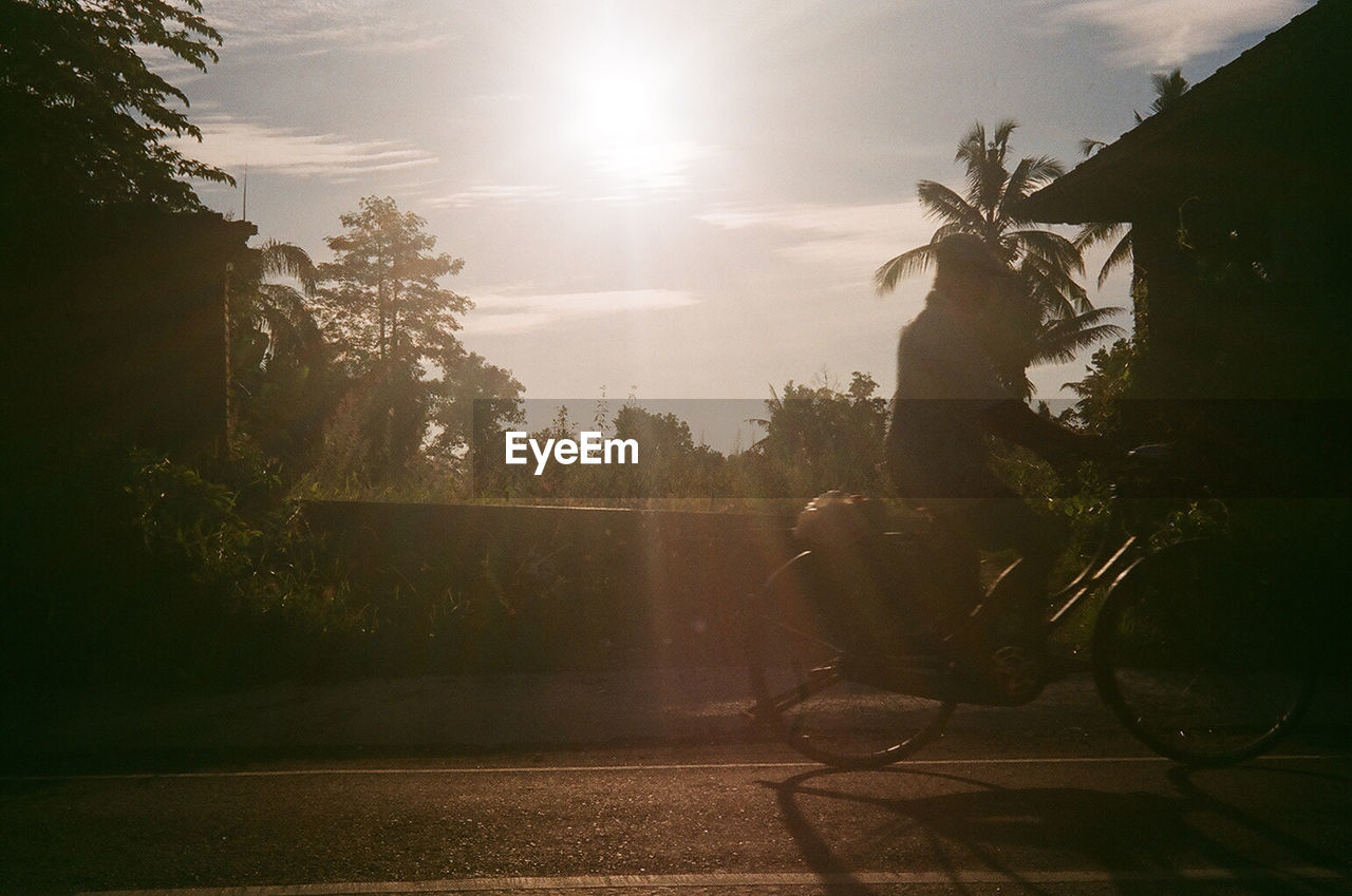 MAN RIDING BICYCLE AGAINST SKY